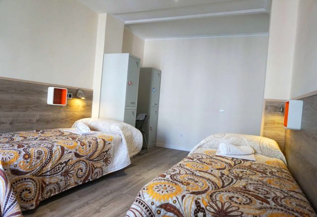 Cama en habitacion cuadruple con baño compartido